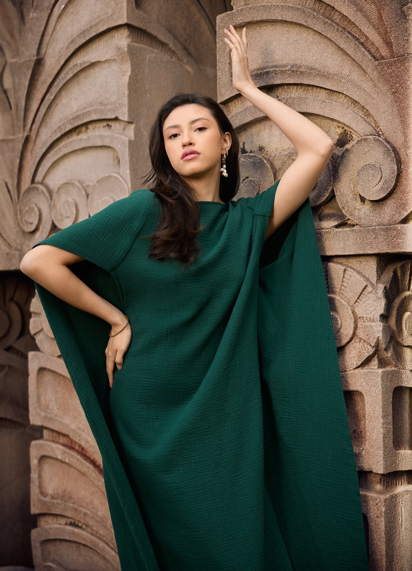 Model wearing a Diana cotton gauze cape caftan in pine green.